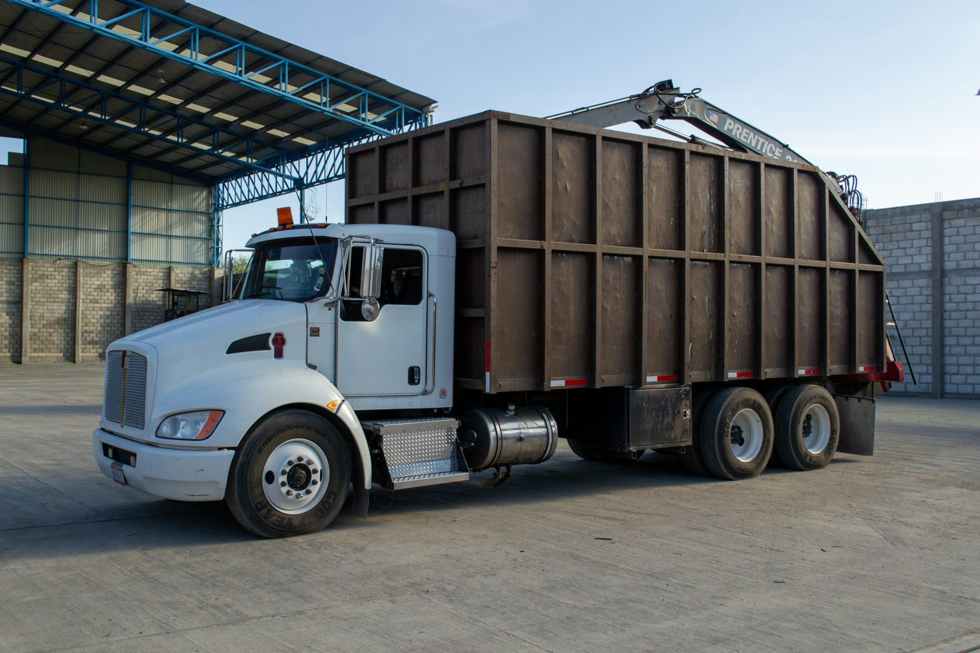 A white truck with a large brown container is parked